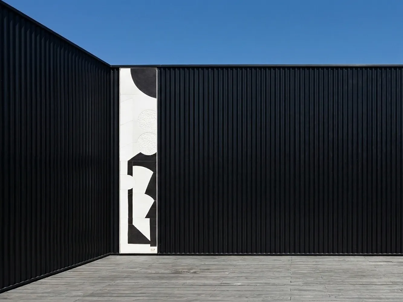 Composition murale Éclipse intégrée à la façade noire d’un studio de photographe à Aubervilliers