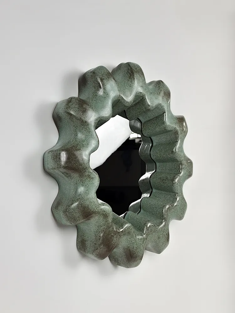 Miroir entouré d’un cadre ondulé en céramique émaillée verte