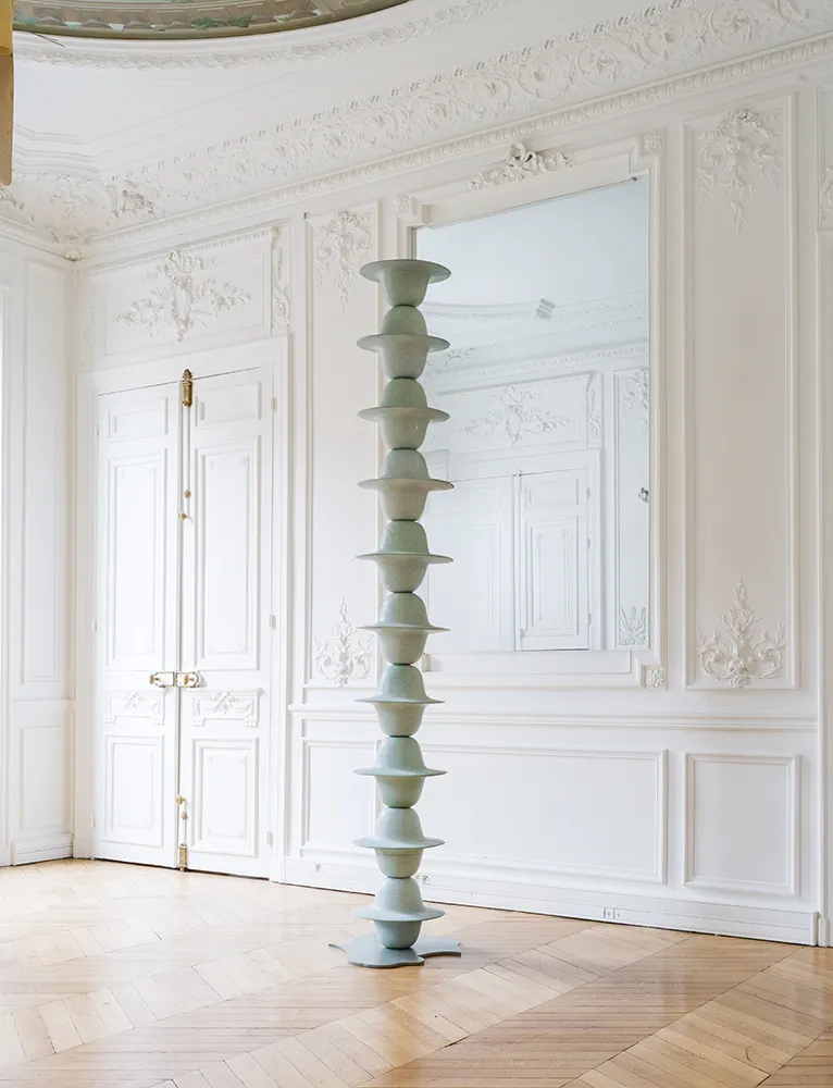 Colonne Pluie en céramique vert pâle installée dans un intérieur parisien aux murs moulurés