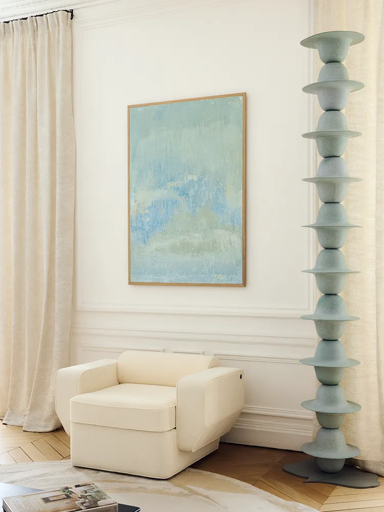 Colonne Pluie en céramique installée entre un fauteuil blanc et un rideau