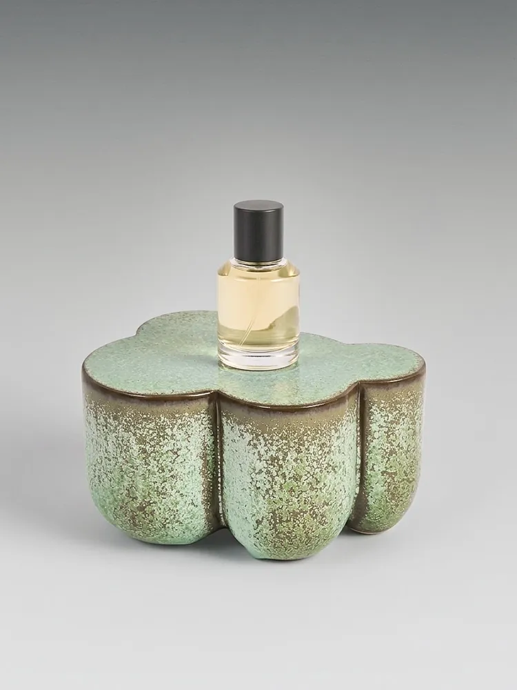 Flacon de parfum posé sur un présentoir en céramique émaillée verte