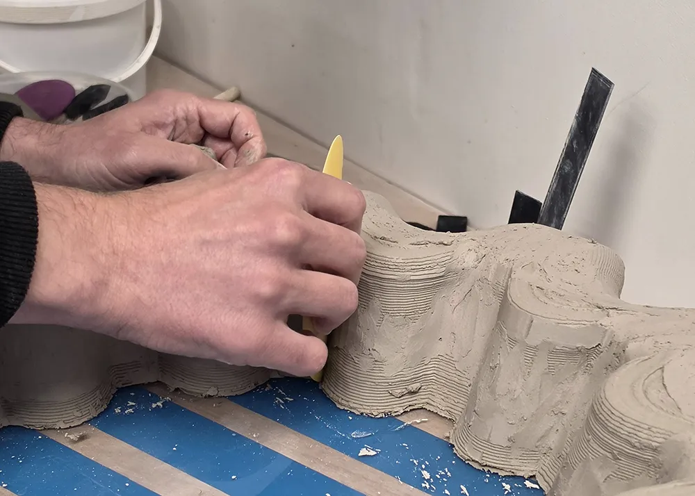 Retouche manuelle d’une pièce en terre après impression 3D